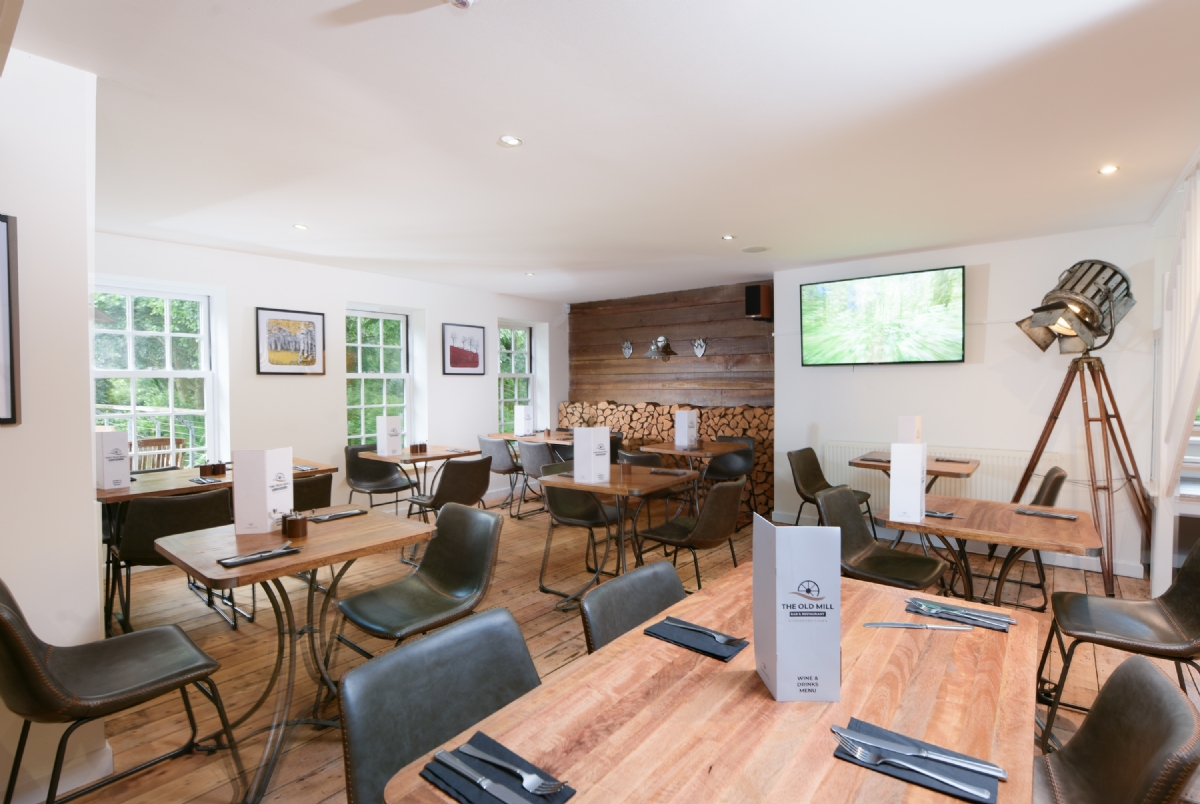 Dining room tables laid for service beside the log wall at The Old Mill