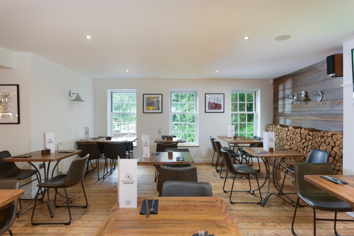 The dining room with wooden tables, leather chairs and a stacked log wall