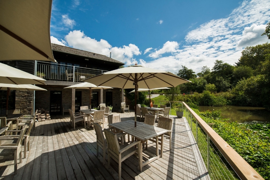 Decked terrace tables under cream parasols looking out over the lake
