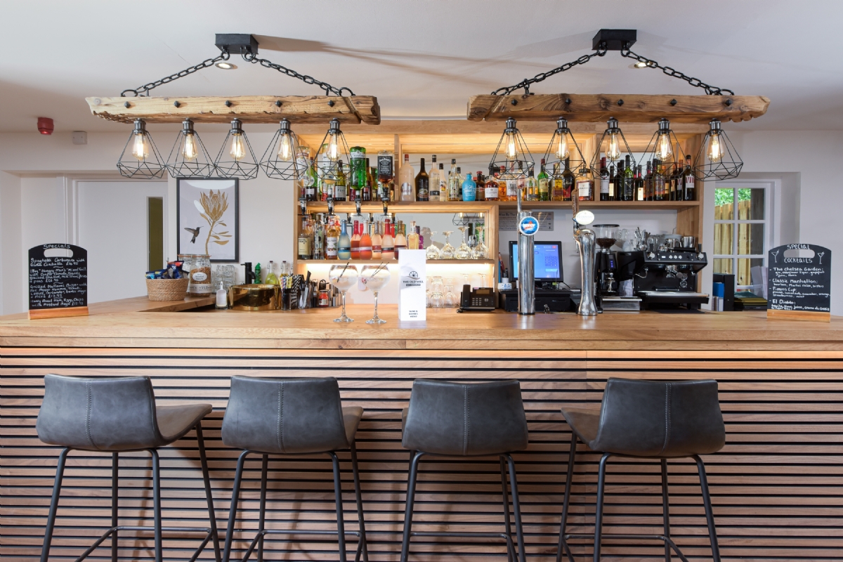 The reclaimed timber bar with hanging cage lights and bar stools
